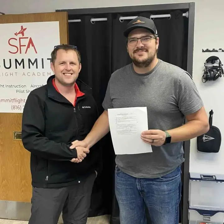 CFI and student holding certificate while they shake hands and smile