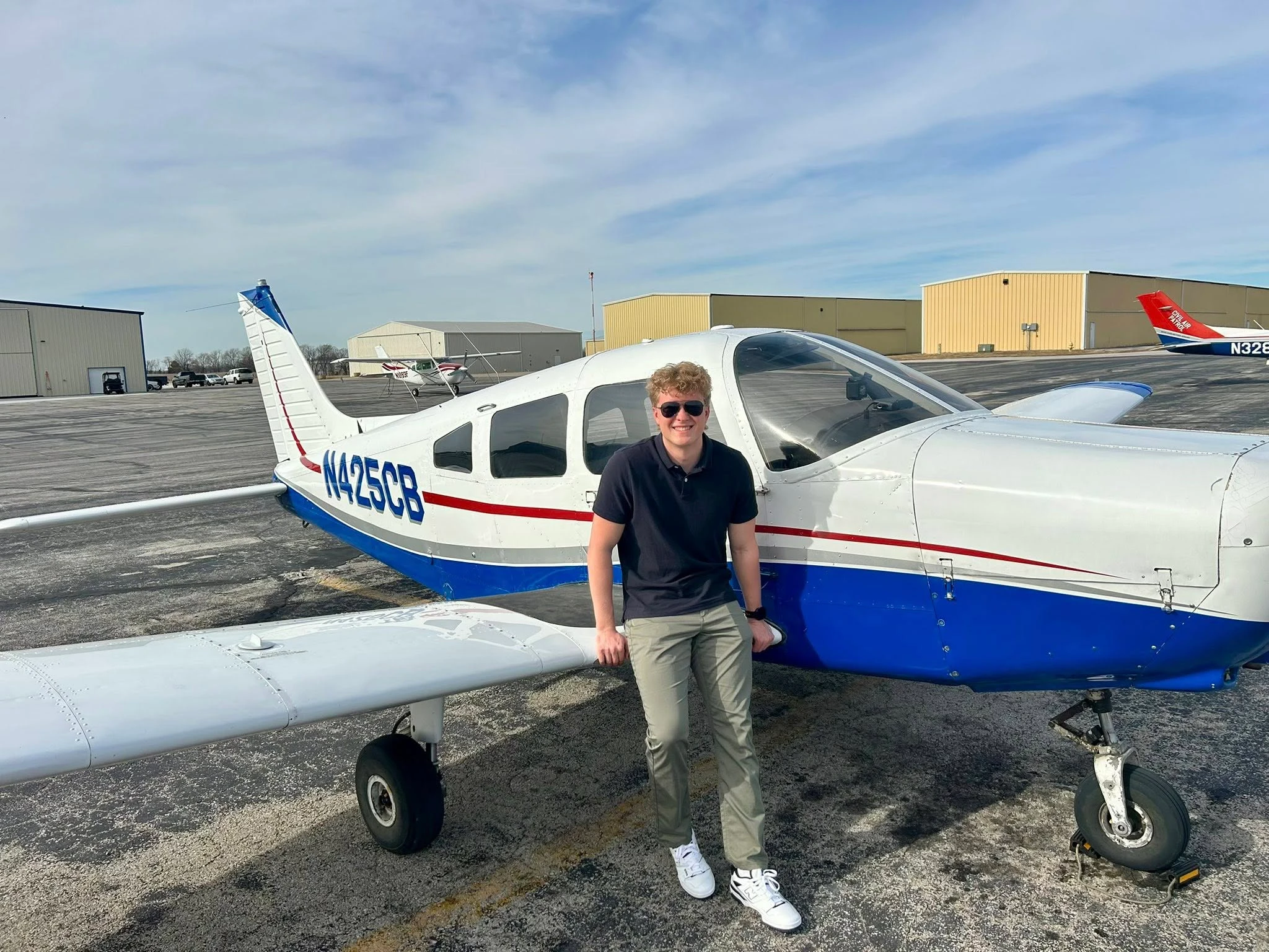 High school student pilot standing next to a Piper aircraft at Lee's Summit Municipal Airport