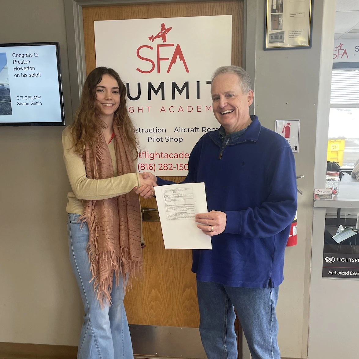 Young student pilot shaking hands with her flight instructor after earning her certificate at Summit Flight Academy