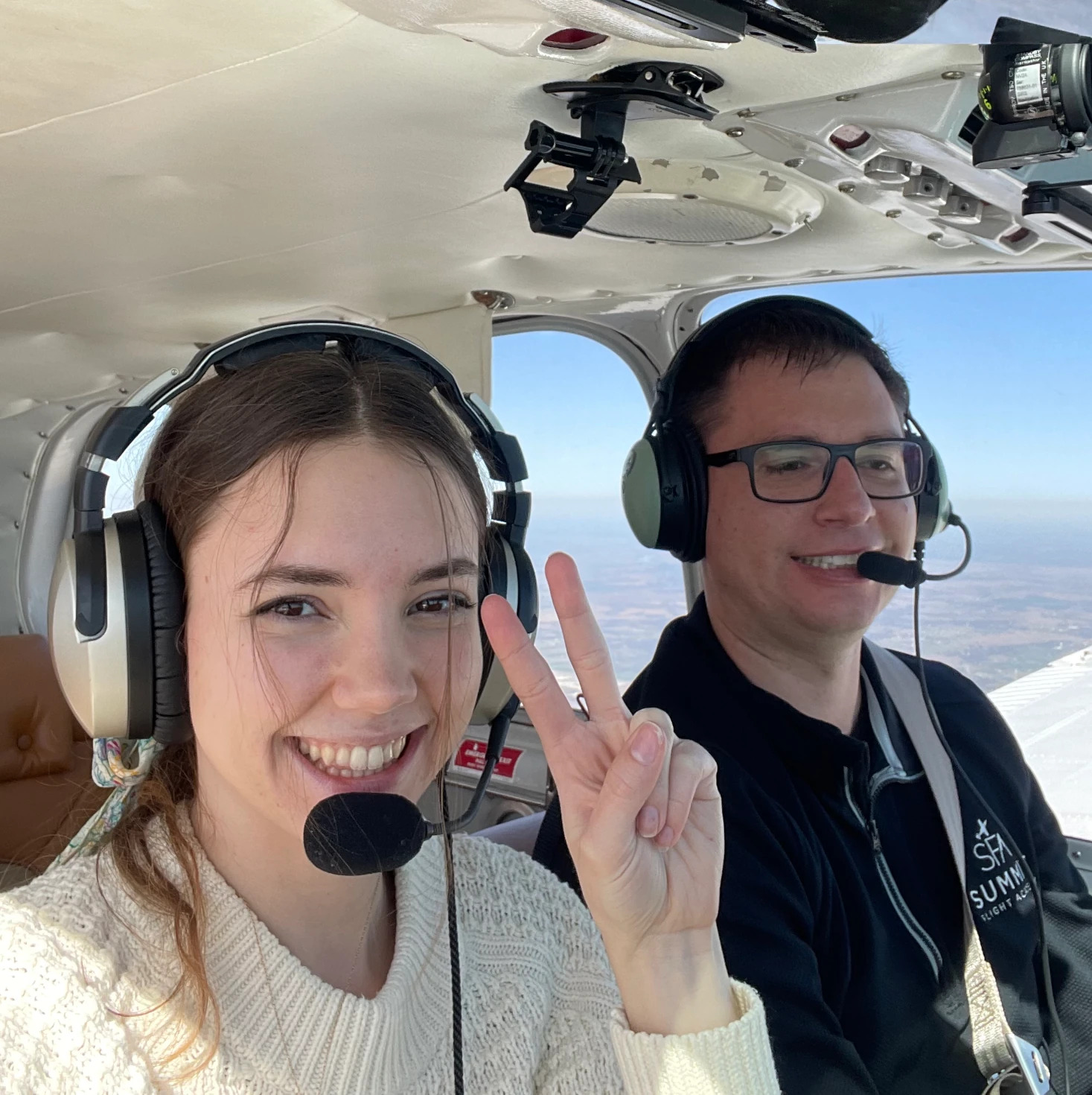 Certified Flight Instructor and student smiling to the camera while in the cockpit flying the plane