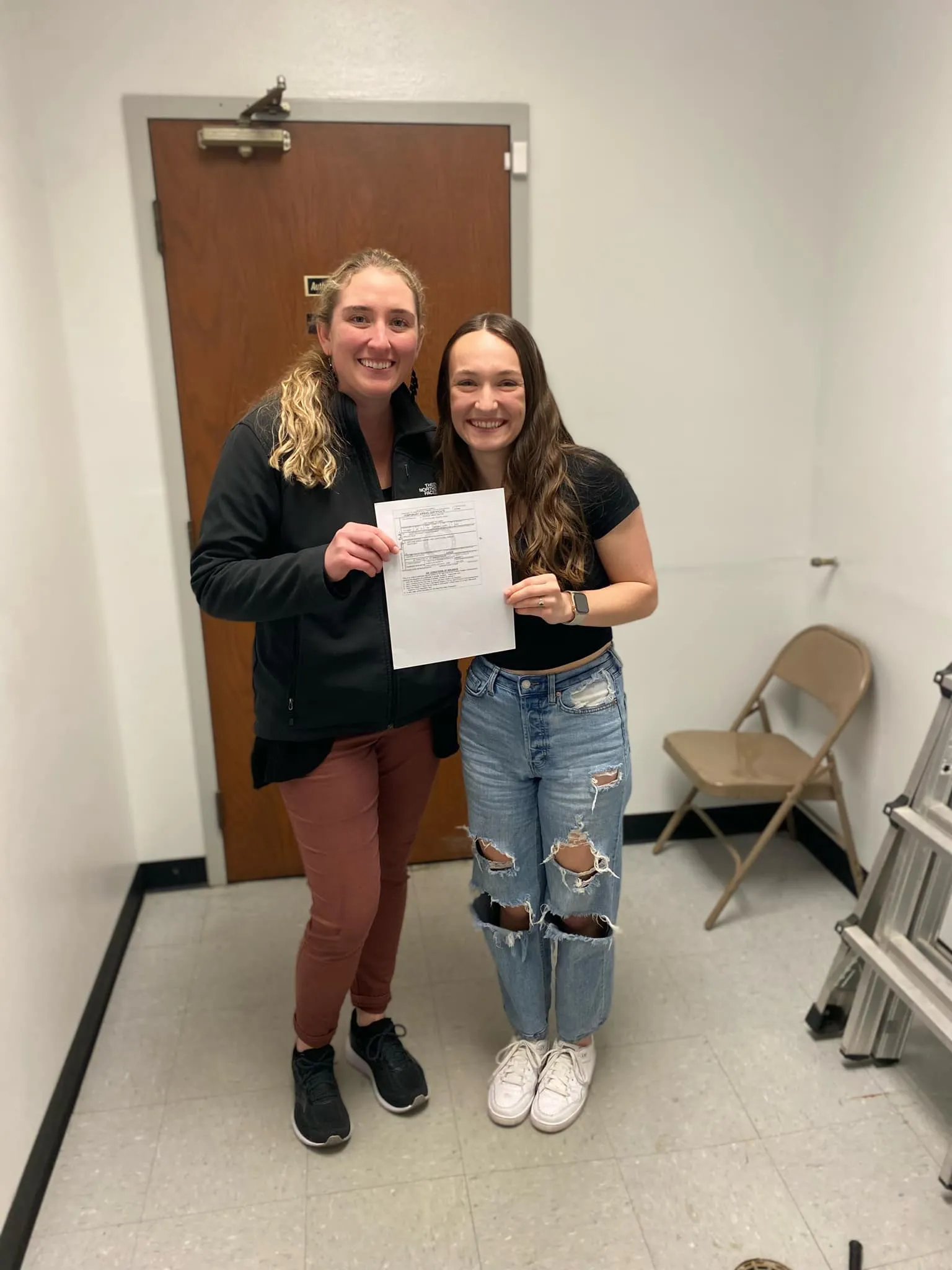 Student and CFI smiling at the camera while holding a certificate