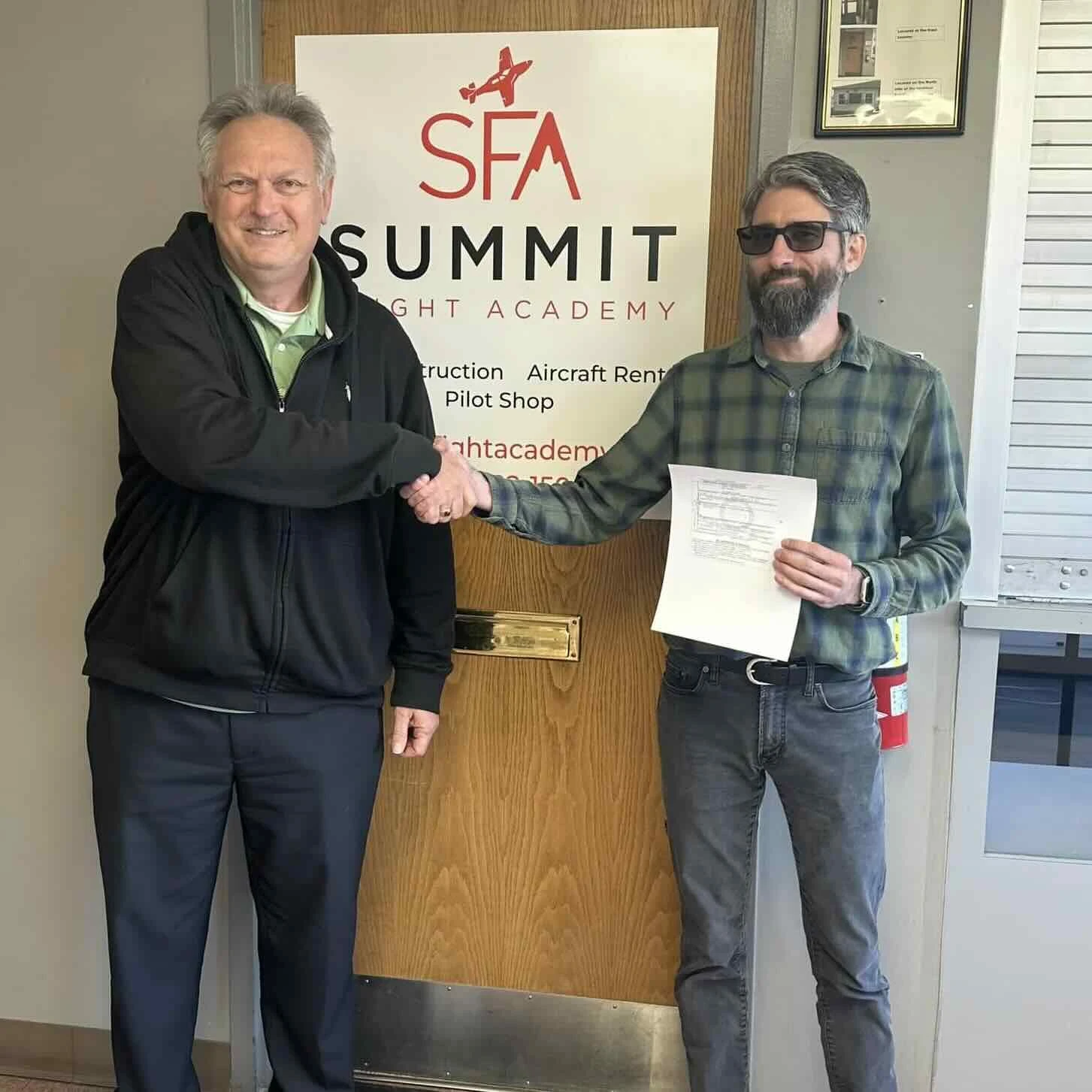 Pilot student shaking hands with instructor while receiving a certificate