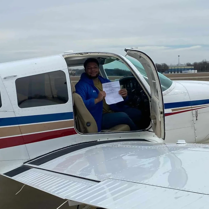 Smiling pilot inside Piper Cherokee cockpit seen trough open door