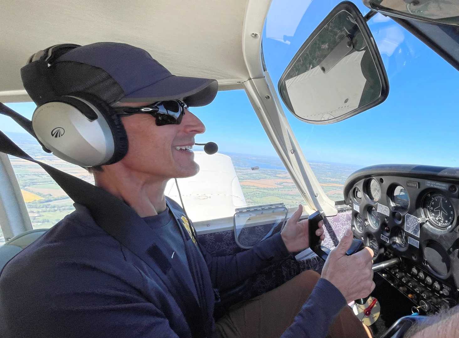 A pilot in the cockpit with hands on the controls